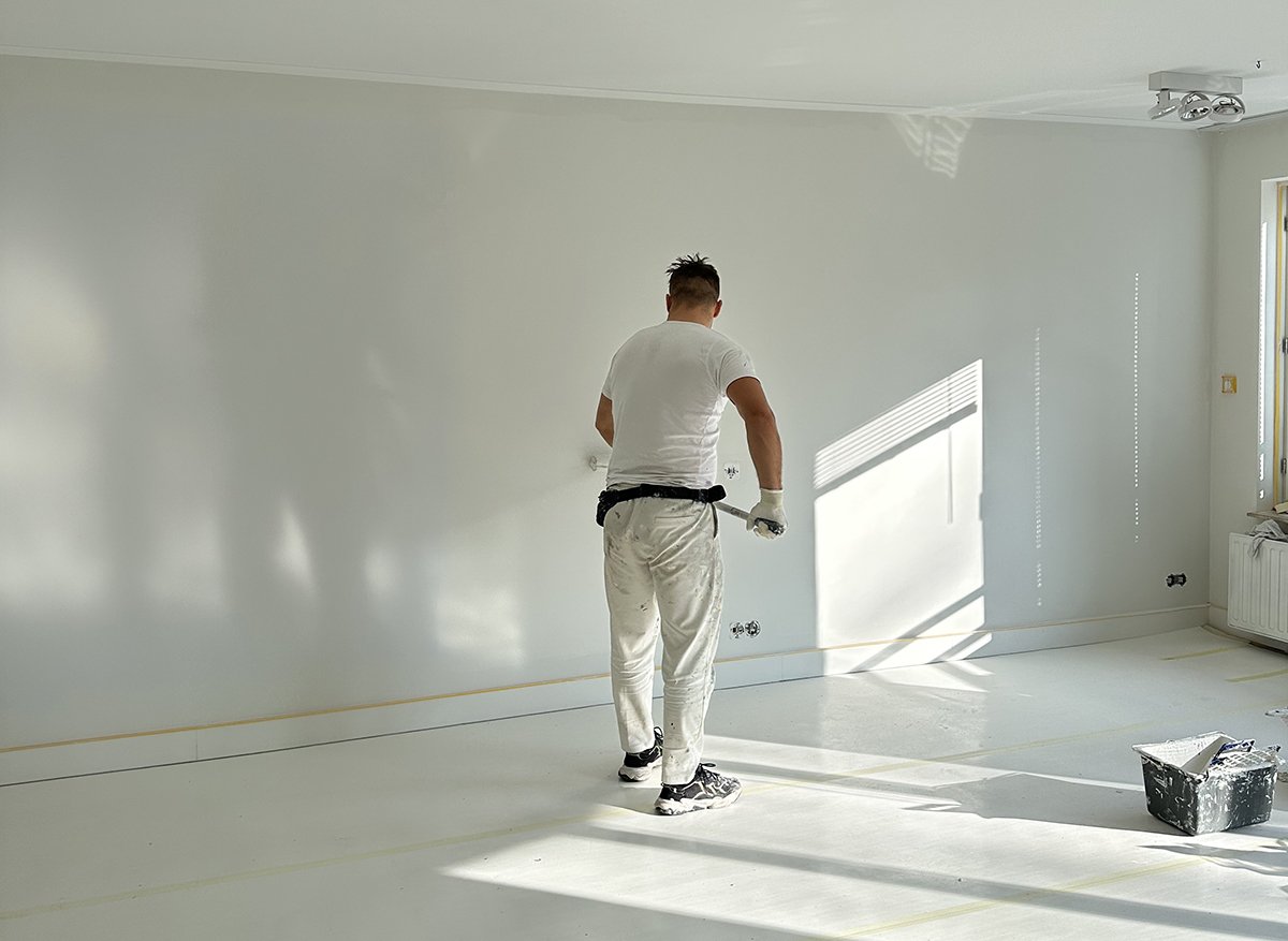 schilder die muur wit aan het schilderen is